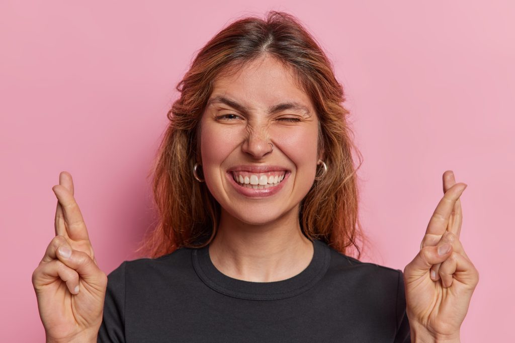 Graceful European lady exudes boundless optimism crossed fingers testament to unwavering hope for